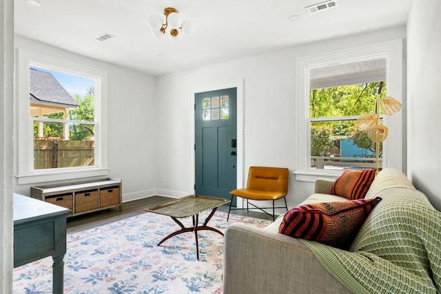 living area with baseboards, wood finished floors, a notable chandelier, and visible vents