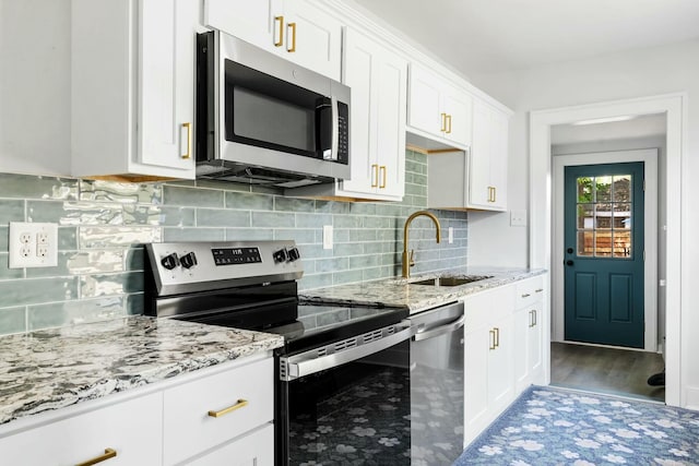 kitchen with light stone countertops, tasteful backsplash, white cabinetry, a sink, and stainless steel appliances