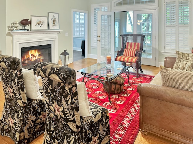 living area with a premium fireplace, light wood-style floors, and baseboards