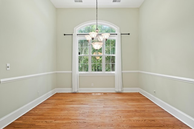 unfurnished room featuring visible vents, baseboards, light wood finished floors, and a notable chandelier