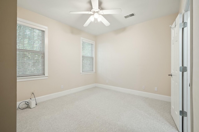 empty room with visible vents, ceiling fan, light carpet, and baseboards