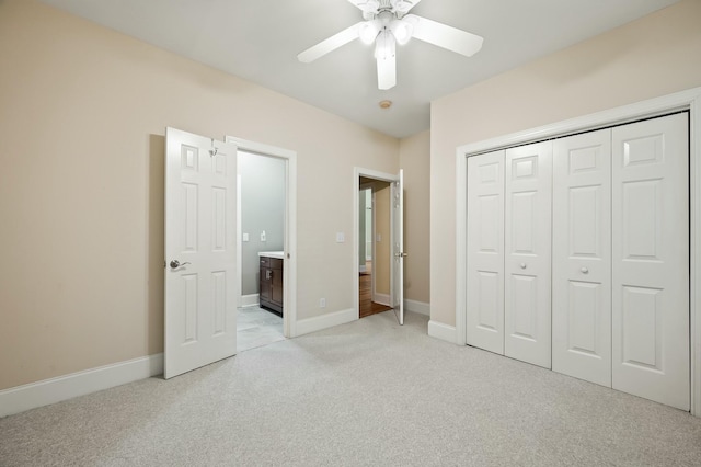 unfurnished bedroom featuring ensuite bathroom, a closet, light colored carpet, a ceiling fan, and baseboards