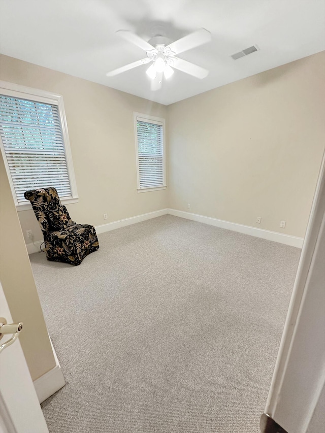 interior space with carpet flooring, visible vents, baseboards, and a ceiling fan