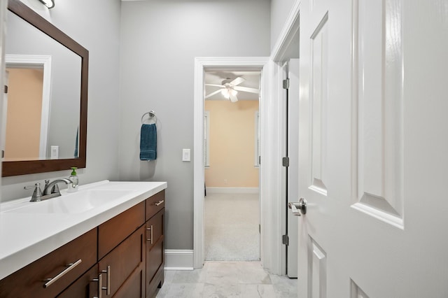 bathroom featuring ceiling fan, baseboards, and vanity