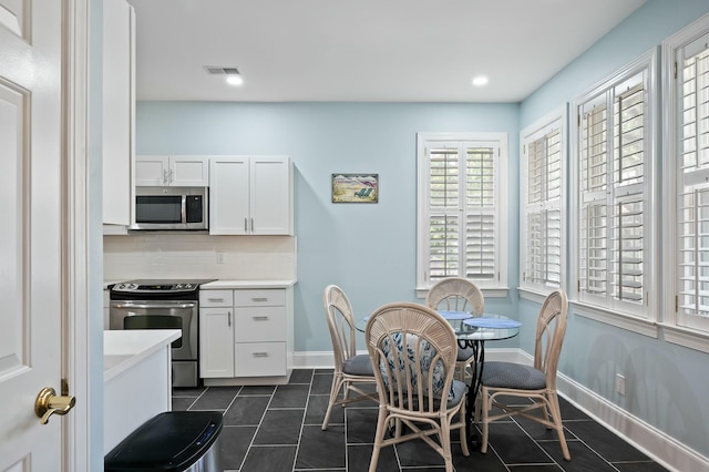 dining space featuring dark tile patterned flooring, baseboards, recessed lighting, and visible vents