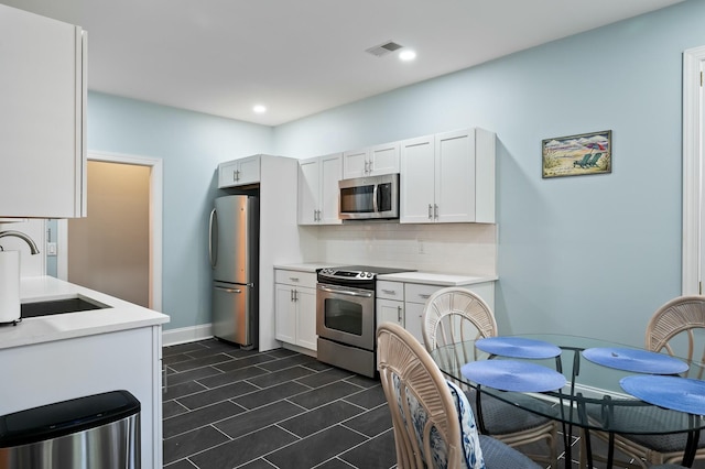 kitchen featuring visible vents, light countertops, a sink, stainless steel appliances, and backsplash