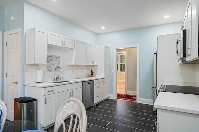 kitchen featuring light countertops, backsplash, white cabinets, appliances with stainless steel finishes, and a sink