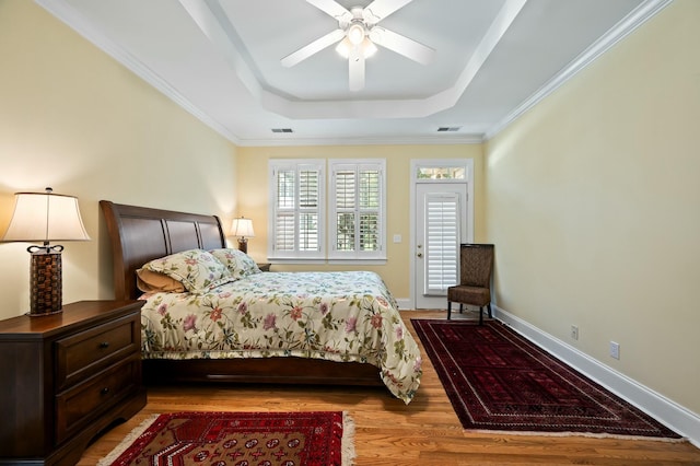 bedroom featuring visible vents, ceiling fan, wood finished floors, and a raised ceiling