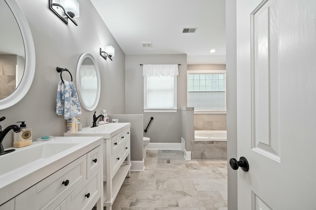 bathroom with two vanities, a bath, visible vents, a sink, and baseboards