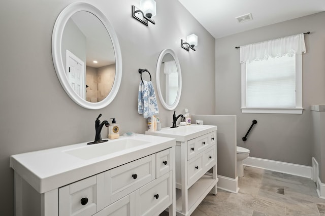 bathroom featuring two vanities, baseboards, toilet, visible vents, and a sink