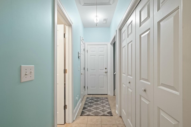 hall featuring light tile patterned floors, baseboards, and attic access