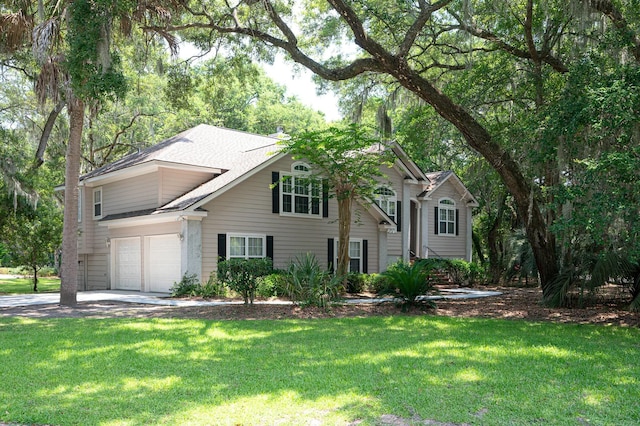 view of front facade featuring a front yard, a shingled roof, a garage, and driveway