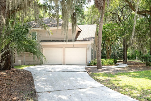 view of front of property with a shingled roof, driveway, and a garage