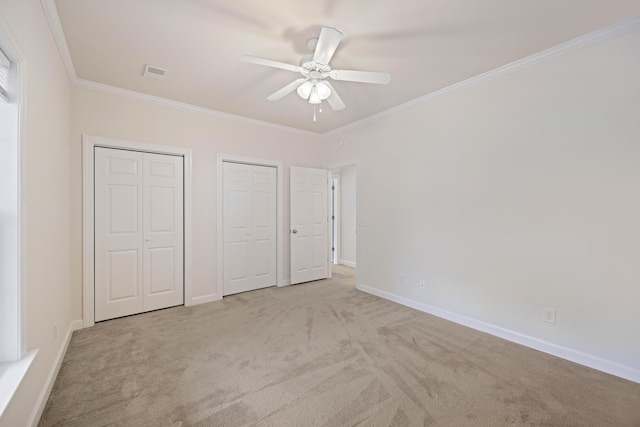 unfurnished bedroom with light carpet, two closets, ceiling fan, and ornamental molding