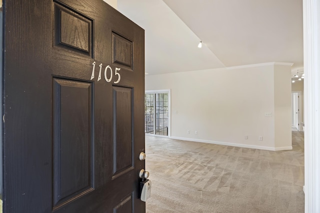 carpeted foyer with ceiling fan, ornamental molding, and vaulted ceiling