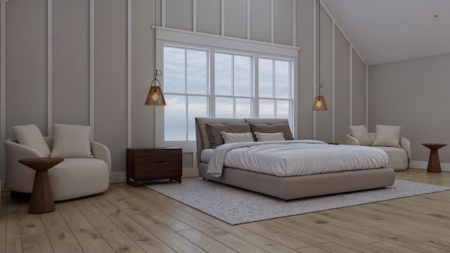 bedroom featuring lofted ceiling, light wood-type flooring, and multiple windows