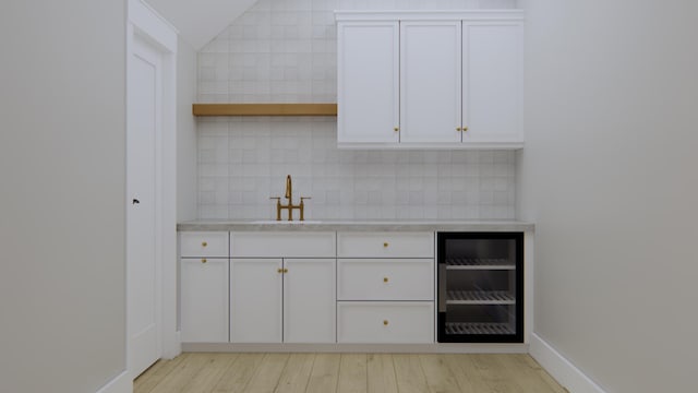 bar featuring white cabinets, wine cooler, decorative backsplash, sink, and light wood-type flooring