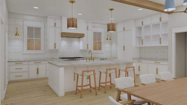 kitchen featuring backsplash, pendant lighting, white cabinets, and a center island with sink