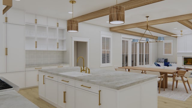 kitchen featuring pendant lighting, white cabinetry, decorative backsplash, sink, and a kitchen island with sink