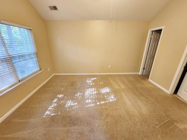 carpeted spare room featuring vaulted ceiling