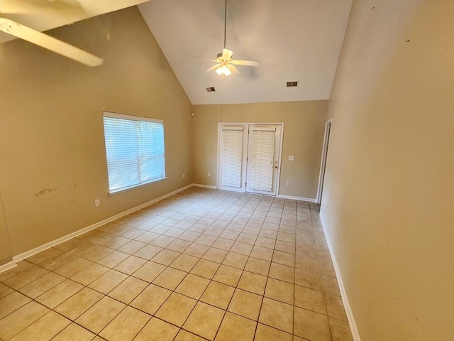 empty room featuring ceiling fan, light tile patterned flooring, and high vaulted ceiling