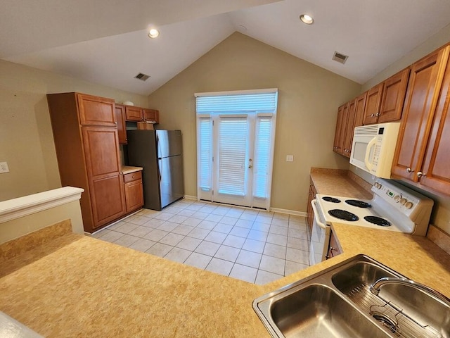 kitchen with lofted ceiling, sink, light tile patterned floors, and white appliances