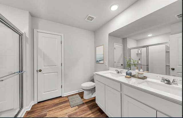 bathroom featuring wood-type flooring, vanity, toilet, and an enclosed shower