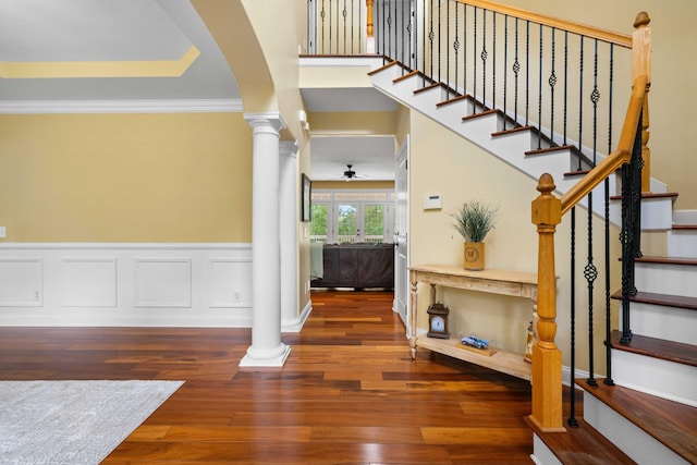 foyer with dark wood-type flooring, ornamental molding, and ornate columns