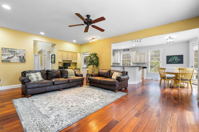 living room featuring dark wood-type flooring and ceiling fan