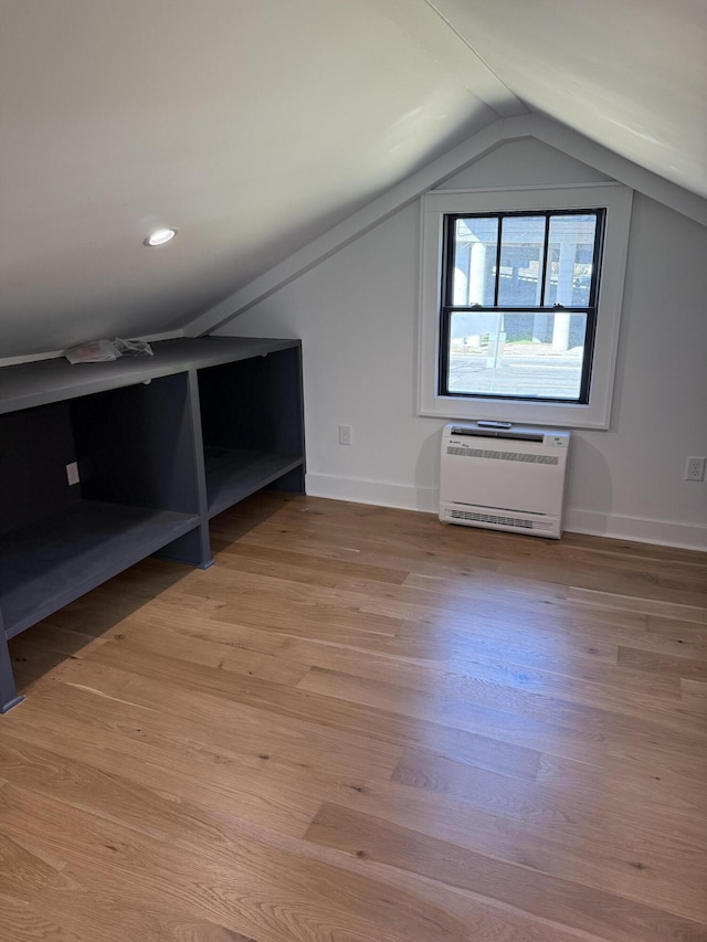 bonus room with heating unit, lofted ceiling, and light wood-type flooring