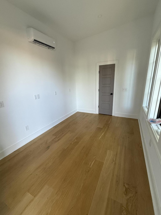 unfurnished room with wood-type flooring and an AC wall unit