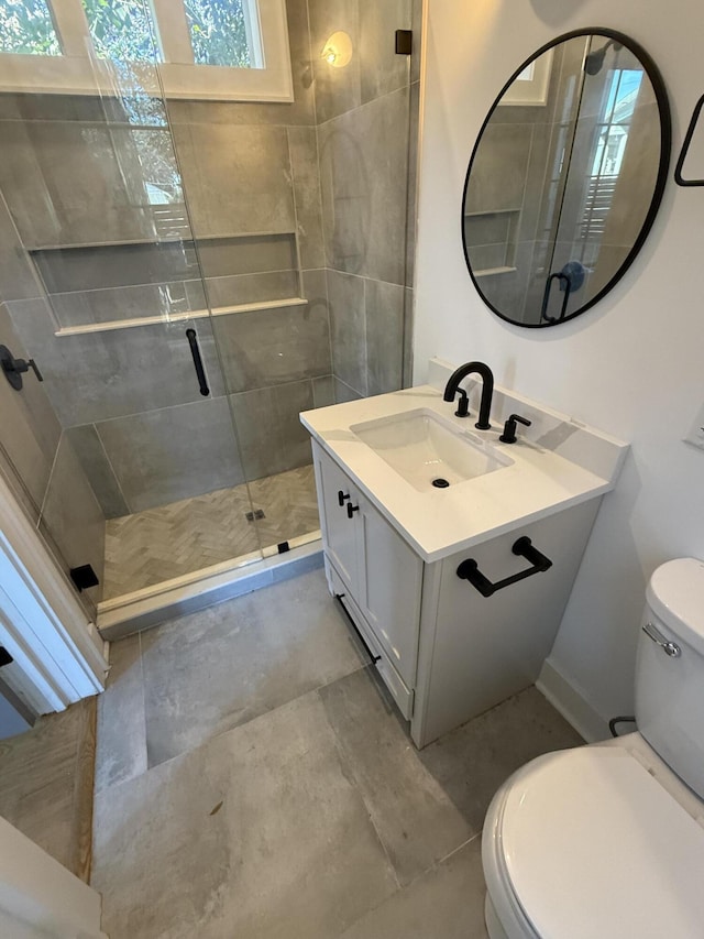 bathroom featuring vanity, toilet, and a shower with door