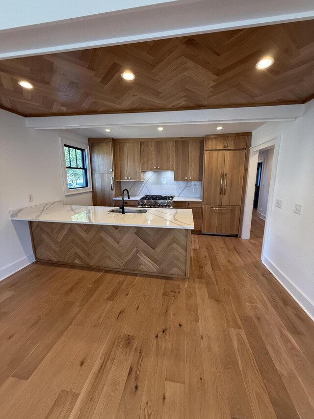 kitchen with sink, decorative backsplash, light hardwood / wood-style floors, and kitchen peninsula