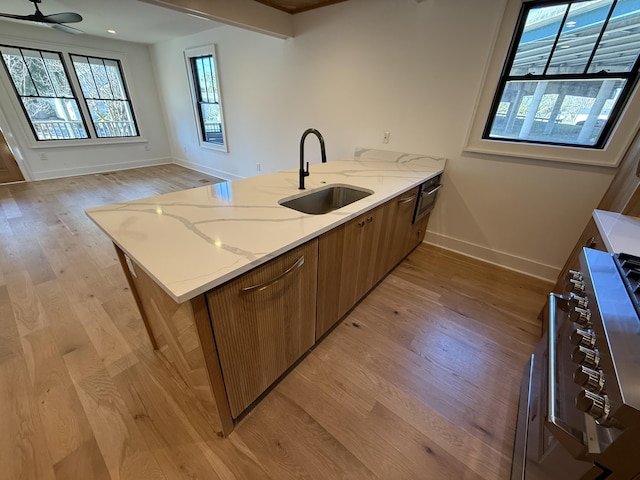 kitchen featuring light hardwood / wood-style floors, sink, light stone countertops, and kitchen peninsula