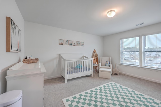 carpeted bedroom featuring a nursery area