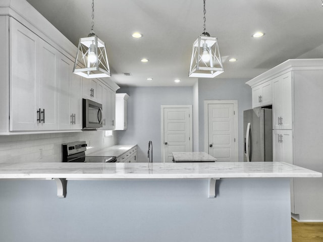 kitchen with hanging light fixtures, a breakfast bar, and appliances with stainless steel finishes