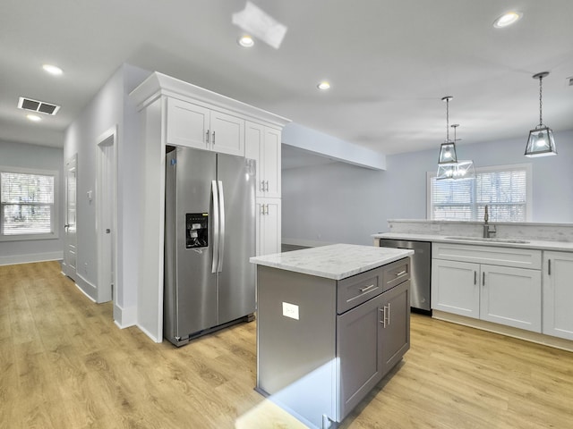 kitchen featuring white cabinetry, appliances with stainless steel finishes, a center island, and sink