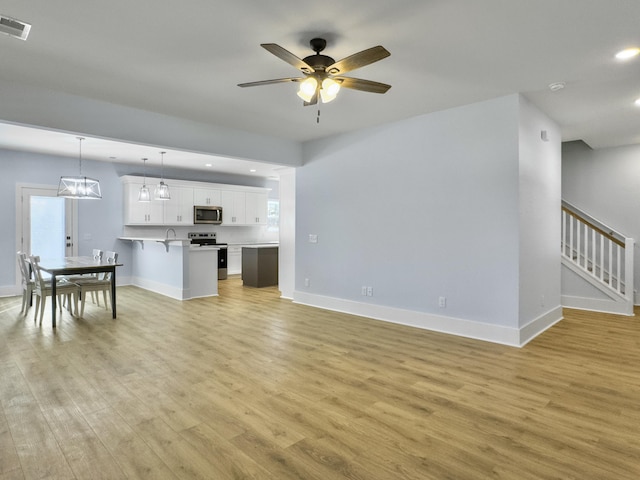 living room with a wealth of natural light, light hardwood / wood-style flooring, and ceiling fan