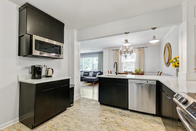 5043 Victoria Ave, North Charleston, SC 29405 - kitchen with appliances with stainless steel finishes, a sink, dark cabinetry, a peninsula, and a chandelier