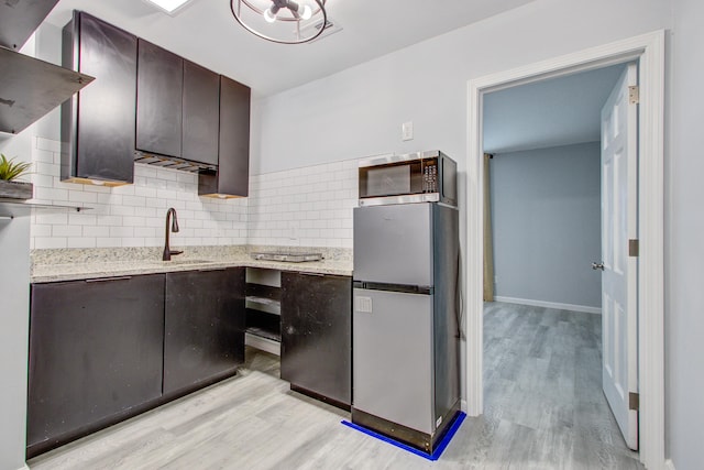 5043 Victoria Ave, North Charleston, SC 29405 - kitchen featuring a sink, light wood-style flooring, appliances with stainless steel finishes, dark brown cabinetry, and backsplash