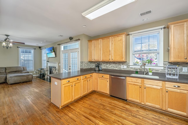 kitchen featuring stainless steel dishwasher, kitchen peninsula, sink, and a wealth of natural light