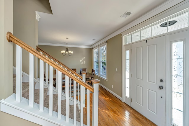 entryway featuring crown molding, light hardwood / wood-style floors, and an inviting chandelier