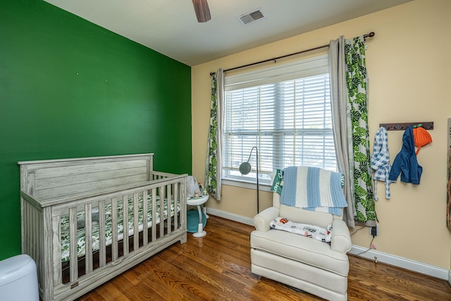 bedroom featuring ceiling fan, dark wood-type flooring, and a nursery area