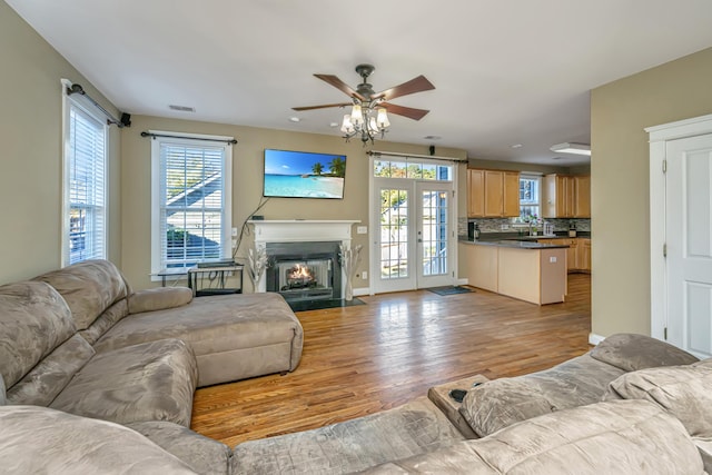 living room featuring french doors, light hardwood / wood-style floors, ceiling fan, and a healthy amount of sunlight