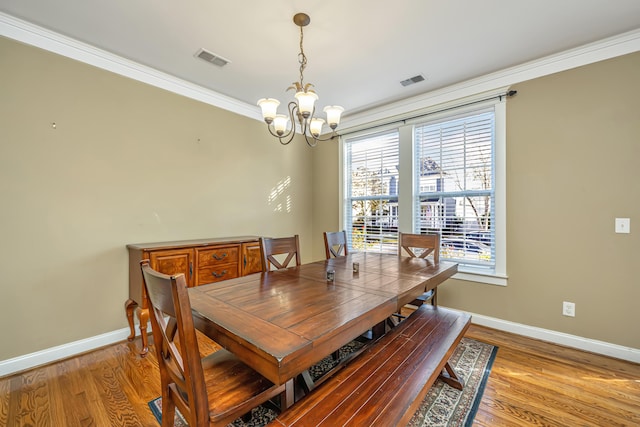 dining space featuring an inviting chandelier, light hardwood / wood-style floors, and ornamental molding