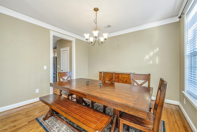 dining room featuring crown molding, an inviting chandelier, and hardwood / wood-style flooring