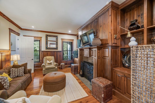 living room with a fireplace, crown molding, and light hardwood / wood-style flooring