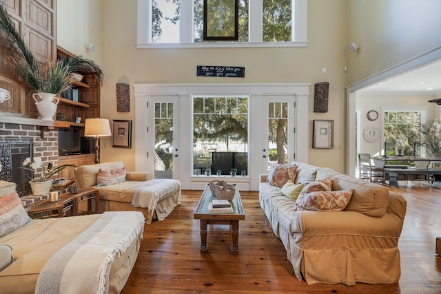 living room featuring hardwood / wood-style floors, a high ceiling, and a brick fireplace