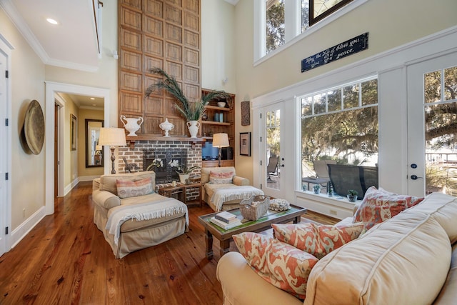 interior space featuring hardwood / wood-style flooring, a towering ceiling, a fireplace, and ornamental molding