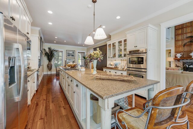 kitchen featuring a kitchen island, white cabinets, hanging light fixtures, and appliances with stainless steel finishes